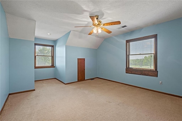 bonus room with a textured ceiling, vaulted ceiling, light colored carpet, and ceiling fan