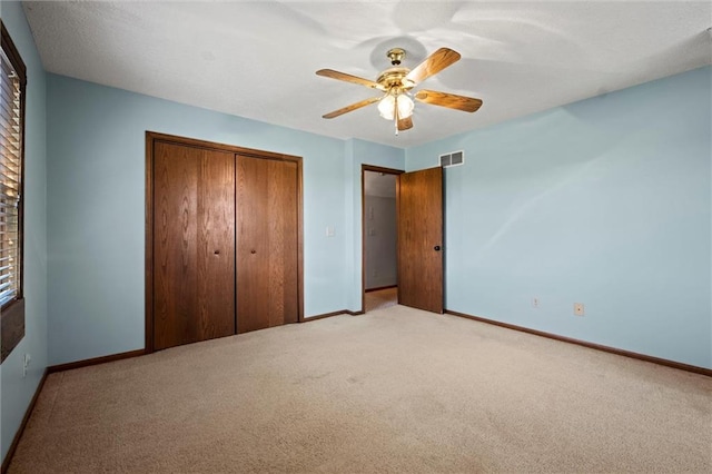 unfurnished bedroom featuring light colored carpet, a closet, and ceiling fan