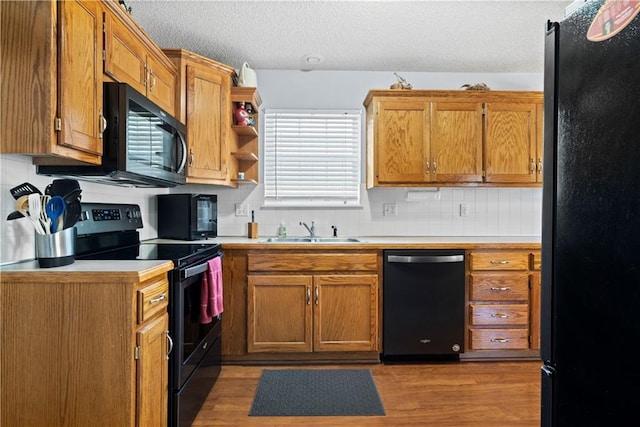 kitchen with black appliances, light countertops, a sink, and brown cabinetry