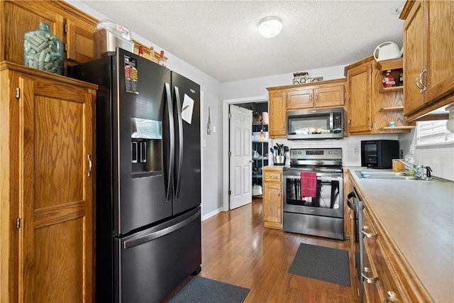 kitchen featuring brown cabinets, stainless steel appliances, light countertops, open shelves, and a sink