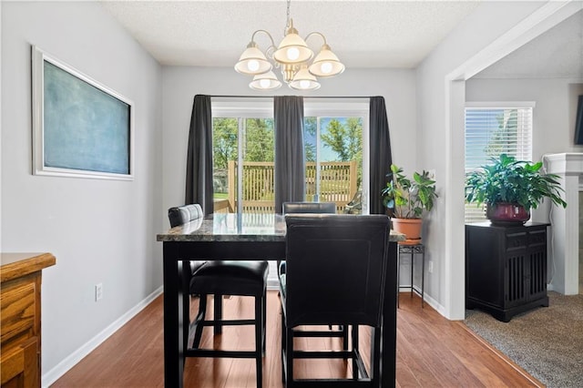 dining room with plenty of natural light, wood finished floors, and an inviting chandelier