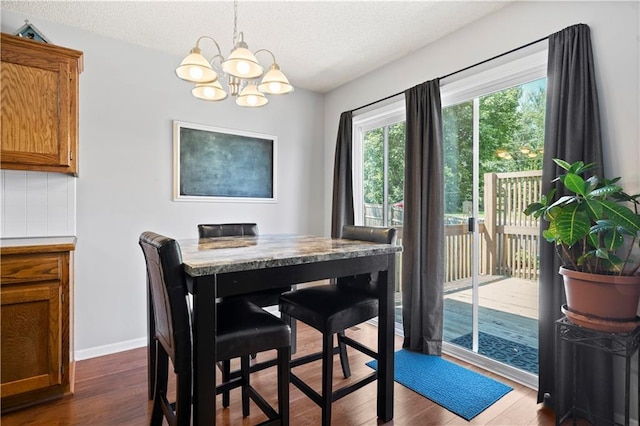 dining room with a notable chandelier, a textured ceiling, dark wood finished floors, and baseboards