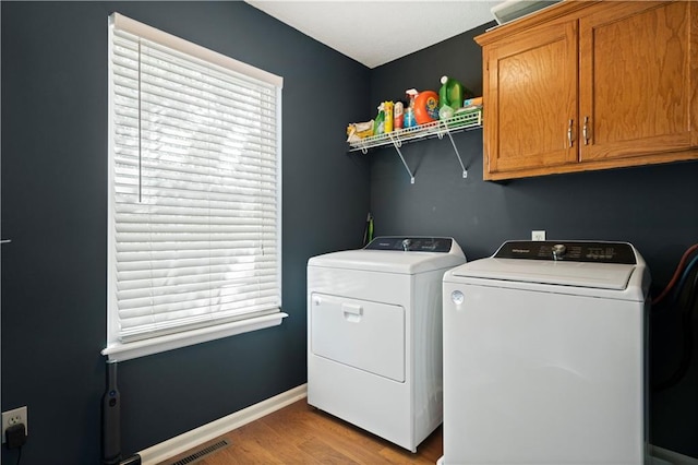 laundry room with a healthy amount of sunlight, cabinet space, visible vents, and washer and dryer