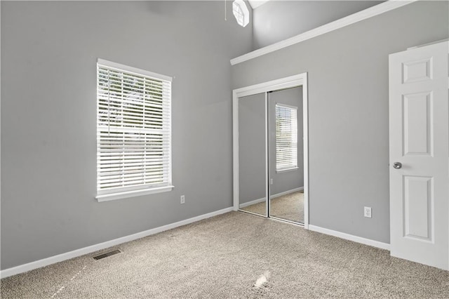 unfurnished bedroom with baseboards, visible vents, a closet, and light colored carpet