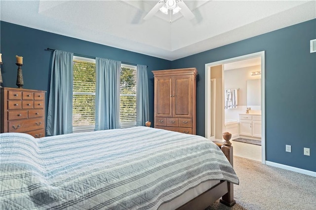 bedroom featuring ceiling fan, baseboards, a raised ceiling, carpet, and ensuite bath