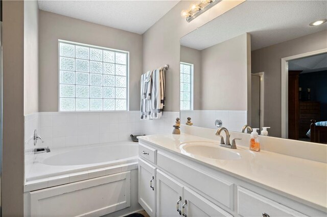 full bath featuring a stall shower, a garden tub, a textured ceiling, and vanity