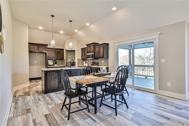 dining room featuring sink, light hardwood / wood-style floors, and vaulted ceiling