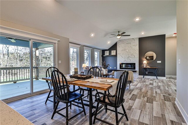 dining room with ceiling fan, a high end fireplace, vaulted ceiling, and hardwood / wood-style floors