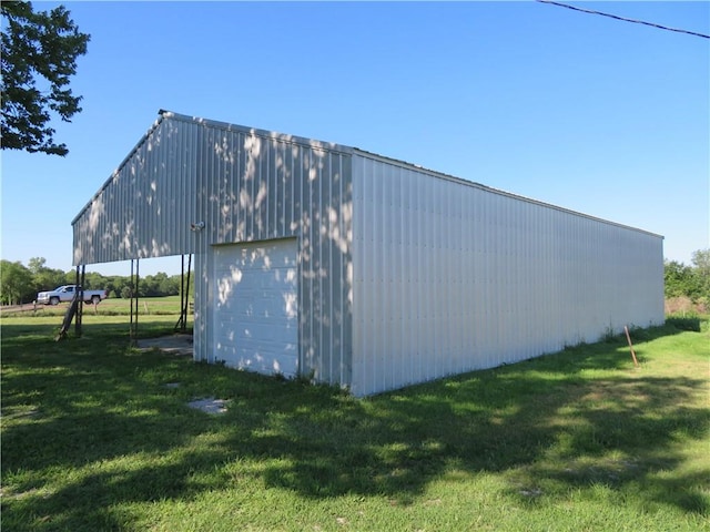 view of side of home featuring a garage, an outbuilding, and a lawn