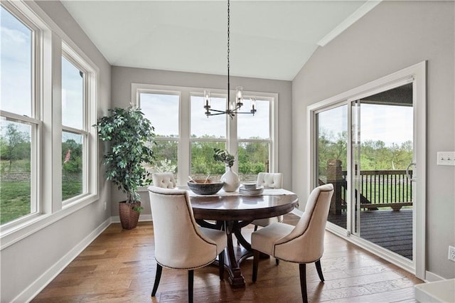 dining room with hardwood / wood-style floors, vaulted ceiling, and an inviting chandelier