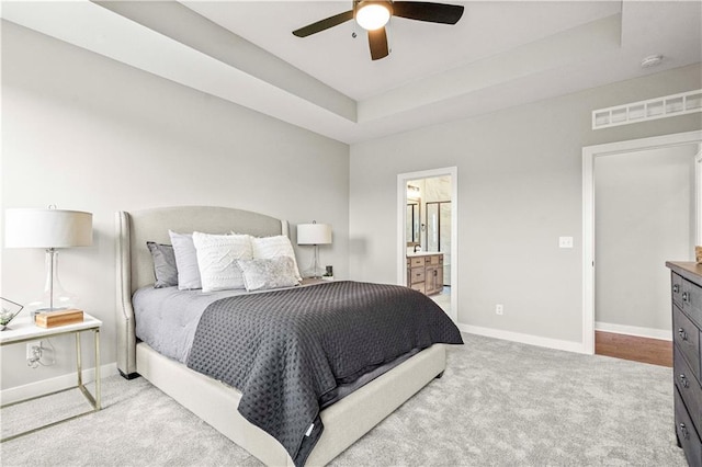 bedroom featuring a tray ceiling, carpet, visible vents, a ceiling fan, and baseboards