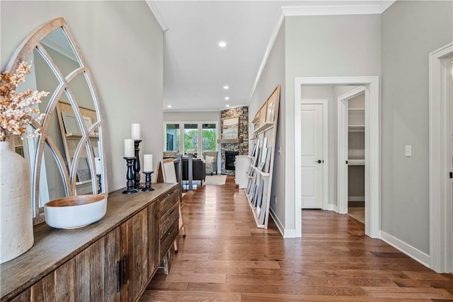 foyer entrance featuring hardwood / wood-style flooring, a stone fireplace, and crown molding