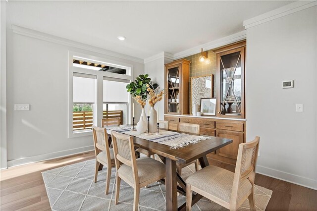 dining room with light hardwood / wood-style floors and crown molding