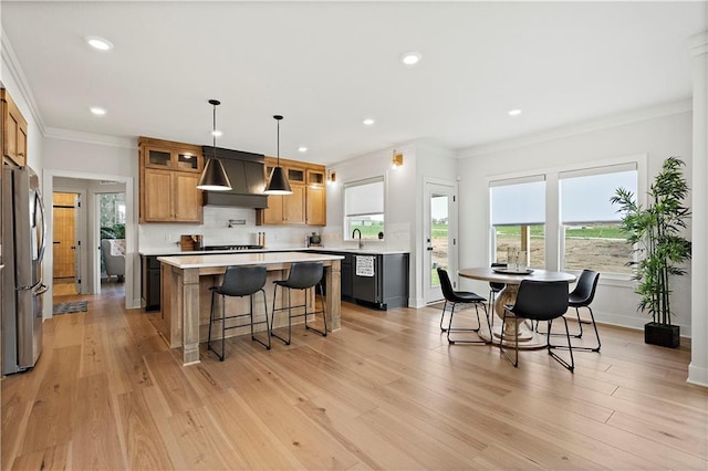 kitchen featuring pendant lighting, stainless steel fridge, a center island, ornamental molding, and exhaust hood