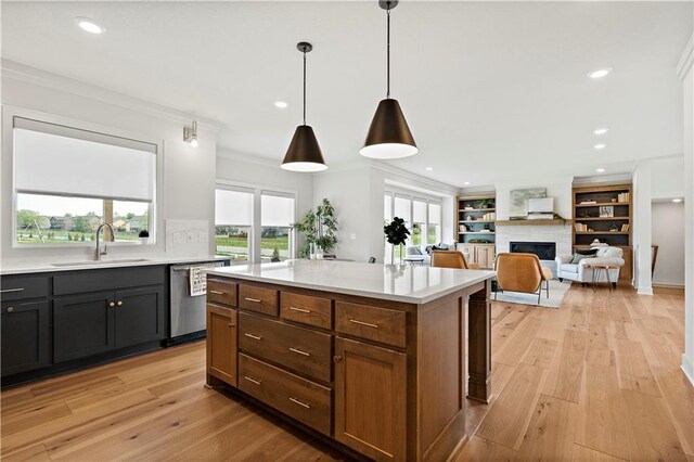 kitchen with light wood-type flooring, dishwasher, sink, decorative light fixtures, and a center island