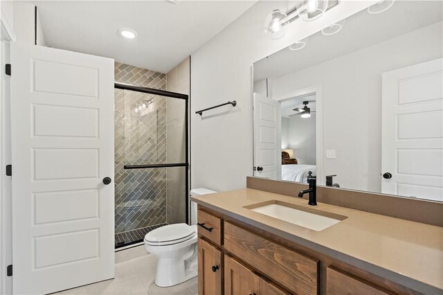 bathroom with ceiling fan, a shower with door, toilet, vanity, and tile patterned floors