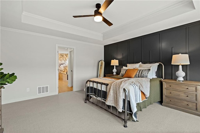 carpeted bedroom featuring crown molding, ceiling fan, and a tray ceiling