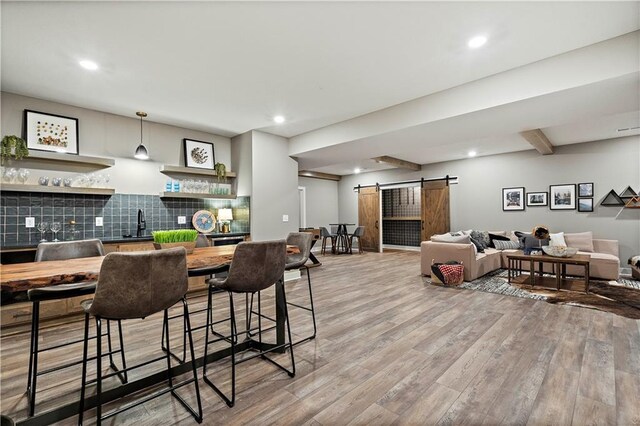 dining area featuring sink, light wood-type flooring, and a barn door