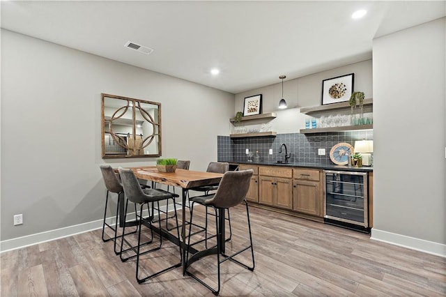 kitchen featuring backsplash, light hardwood / wood-style flooring, sink, pendant lighting, and beverage cooler