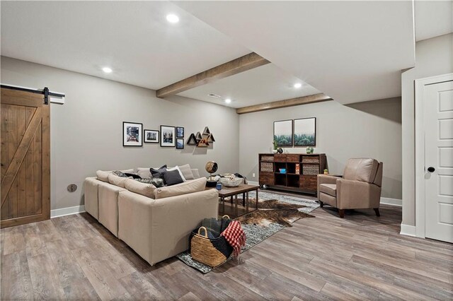 living room with hardwood / wood-style flooring, beamed ceiling, and a barn door