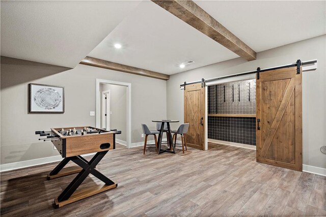 recreation room with hardwood / wood-style floors, beamed ceiling, and a barn door