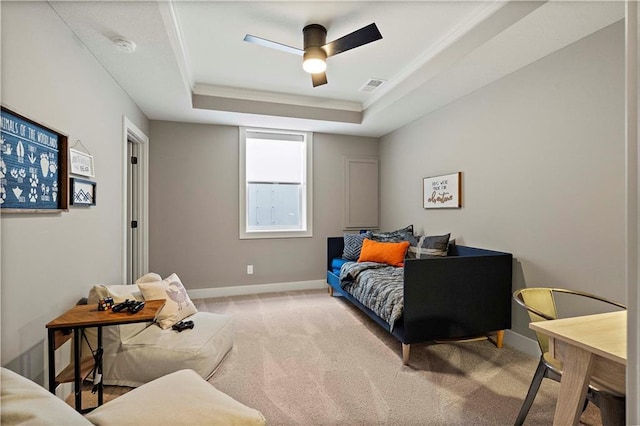 carpeted bedroom with crown molding, a tray ceiling, and ceiling fan