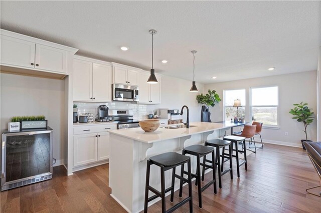 kitchen with a kitchen island with sink, appliances with stainless steel finishes, sink, and wood-type flooring