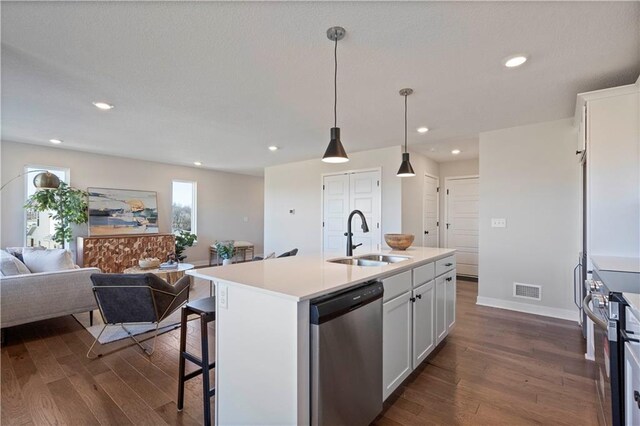 kitchen featuring appliances with stainless steel finishes, a kitchen island with sink, white cabinetry, and dark hardwood / wood-style flooring