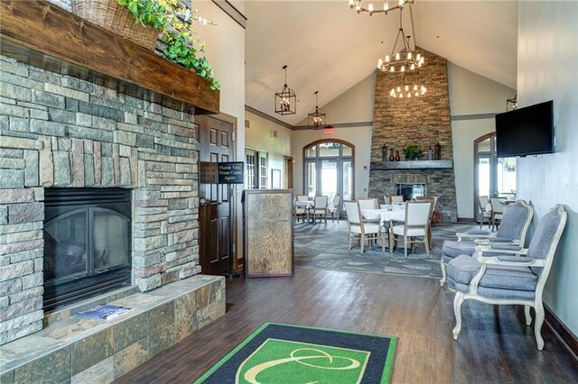 living room featuring a fireplace, high vaulted ceiling, an inviting chandelier, and dark hardwood / wood-style floors