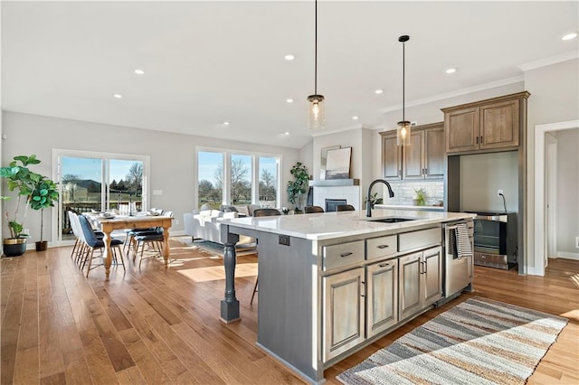 kitchen with sink, light stone counters, decorative backsplash, an island with sink, and light hardwood / wood-style floors