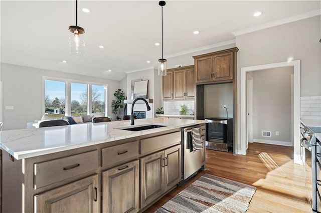 kitchen featuring appliances with stainless steel finishes, sink, a kitchen island with sink, and light stone counters