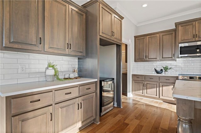 kitchen featuring backsplash, dark wood-type flooring, wine cooler, and crown molding