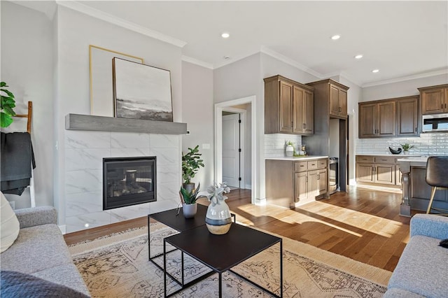 living room featuring light hardwood / wood-style floors, ornamental molding, and a tile fireplace