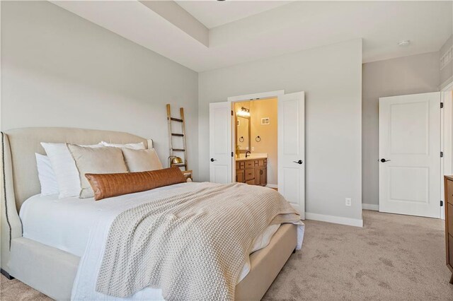 bedroom featuring sink, light carpet, and ensuite bath