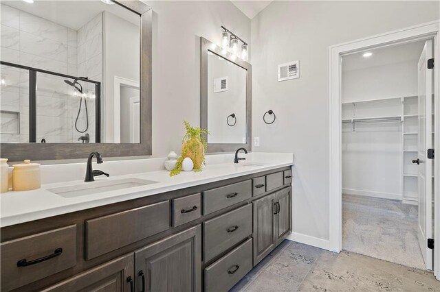 bathroom with tiled shower, double vanity, and tile patterned floors