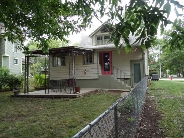 view of front of property featuring central AC unit, fence, and a front yard