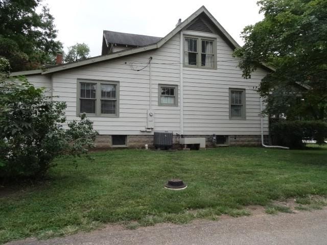 rear view of property featuring cooling unit and a yard