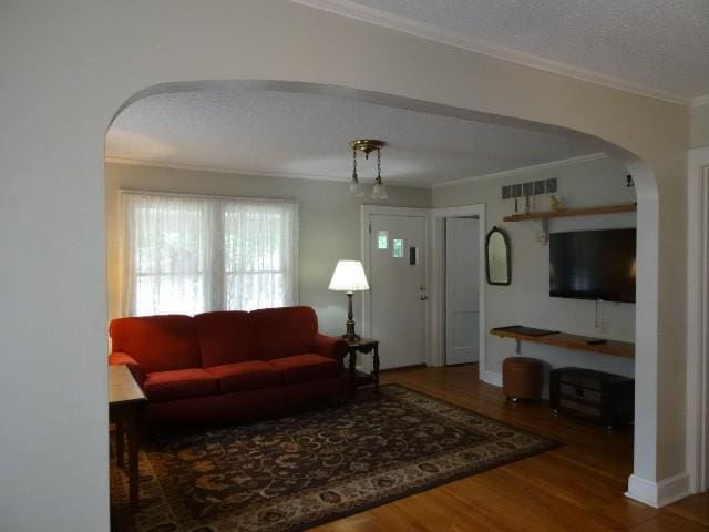 living room with a textured ceiling, crown molding, and hardwood / wood-style floors