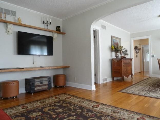 living room featuring a textured ceiling, crown molding, and hardwood / wood-style floors