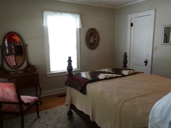 bedroom with ornamental molding and wood-type flooring