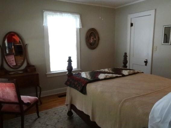 bedroom with light wood-style floors, crown molding, and baseboards