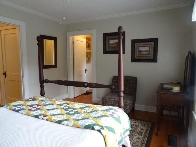 bedroom with baseboards, wood finished floors, and crown molding