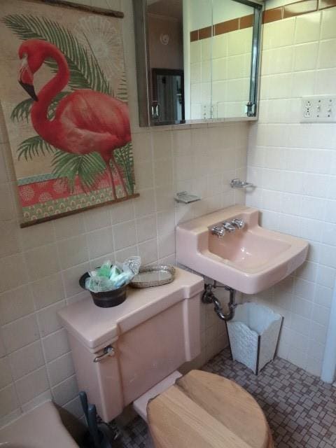 bathroom featuring a sink, tasteful backsplash, and tile walls