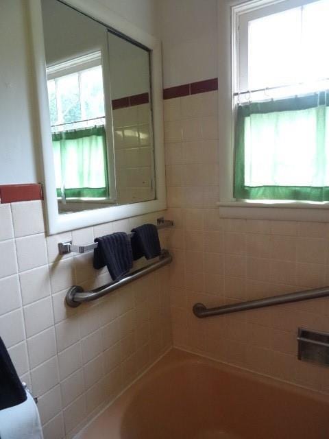 bathroom with a washtub and tile walls