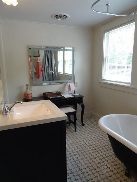 home office featuring ornamental molding, a sink, visible vents, and baseboards