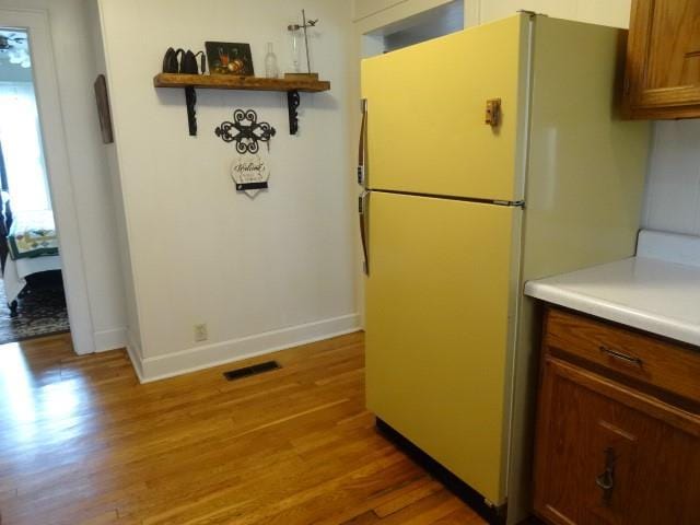 kitchen with baseboards, visible vents, freestanding refrigerator, light wood-type flooring, and open shelves