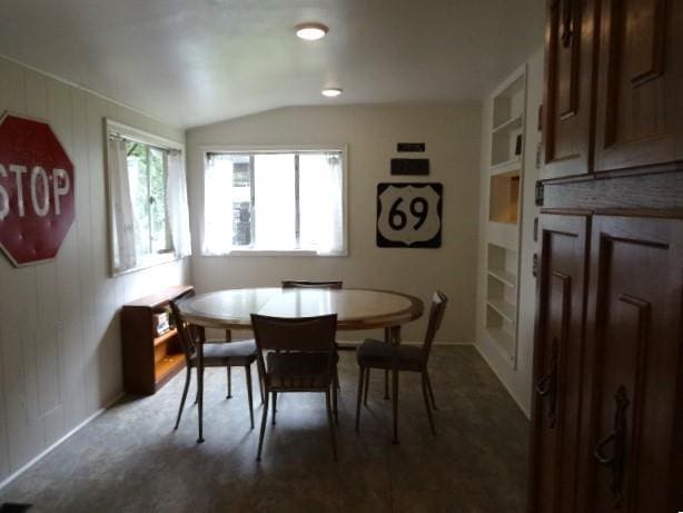 carpeted dining area featuring vaulted ceiling