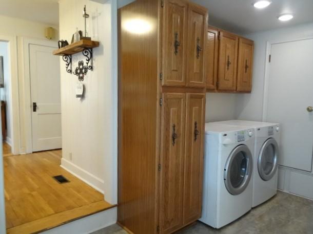 laundry area with light wood-type flooring, cabinets, and washing machine and clothes dryer