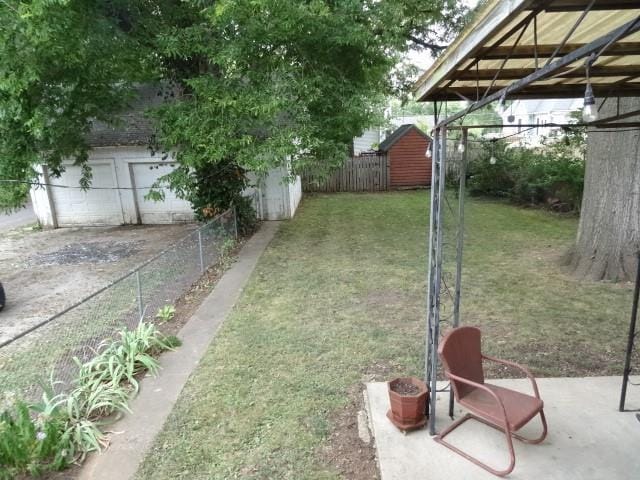 view of yard featuring a garage, fence, and an outbuilding