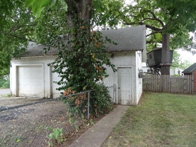 view of side of home with a lawn, a garage, and an outbuilding